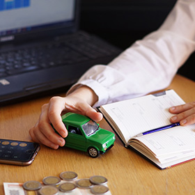 A Man Holding a Toy Car and a Notebook